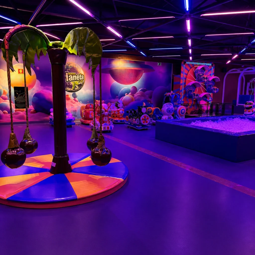 Área de brincadeiras coberta com brinquedos e iluminação colorida para crianças